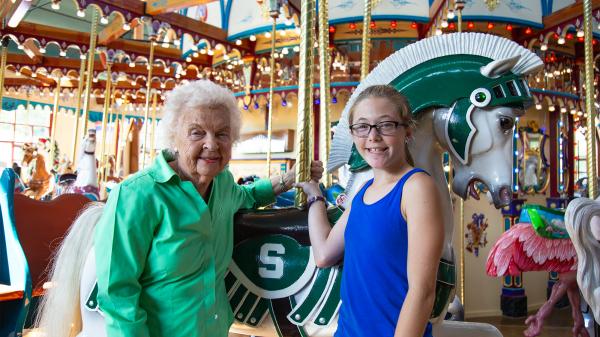 1 Millionth Rider standing with Marcie Schalon in front of Sparty